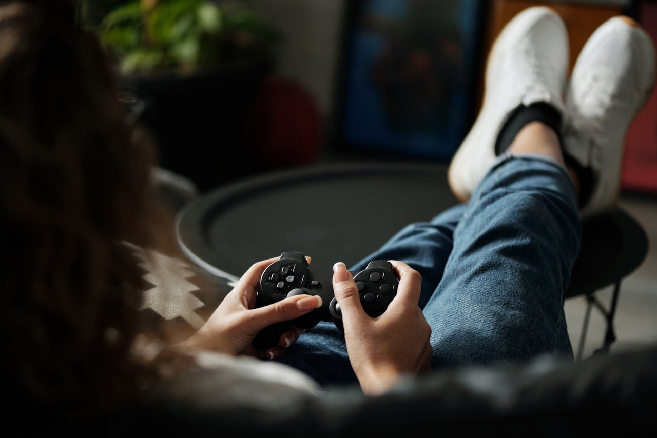 Close-up of woman gaming with a controller, feet propped up, enjoying leisure time indoors.